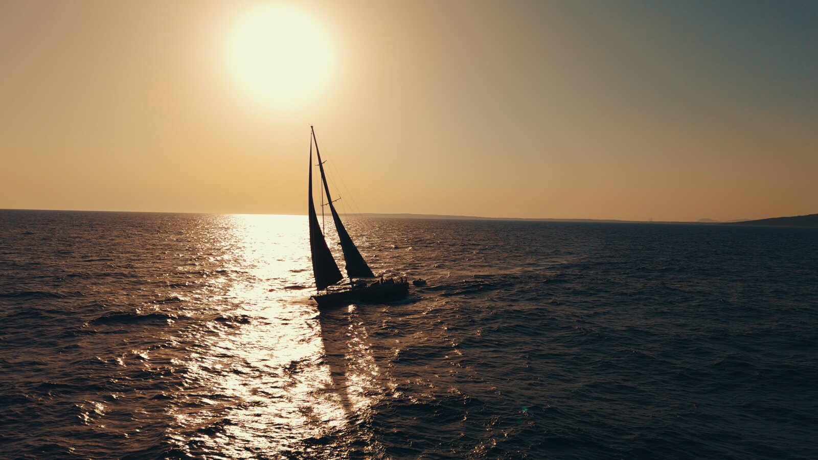 A boat under sail at sunset off Formentera